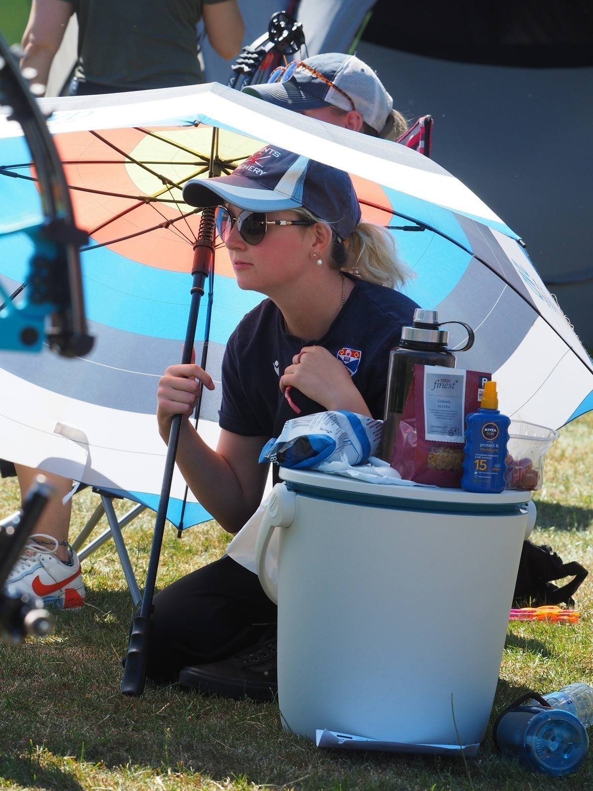 Archer wearing sunglasses and a cap in the shade on a sunny day