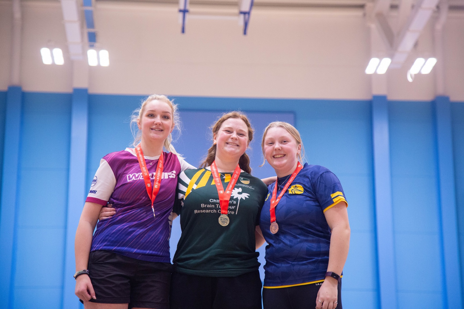 Three student archers wearing medals